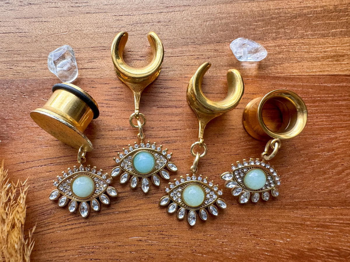 Gold Oracle's Eye plug earrings with detailed mystical eye inspired dangle charms for stretched ears.