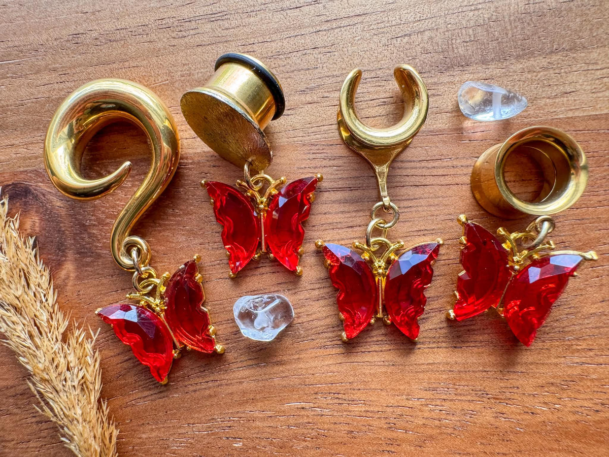Gold and red butterfly dangling plug earrings featuring vibrant red butterfly details and gold-tone accents for stretched ears.