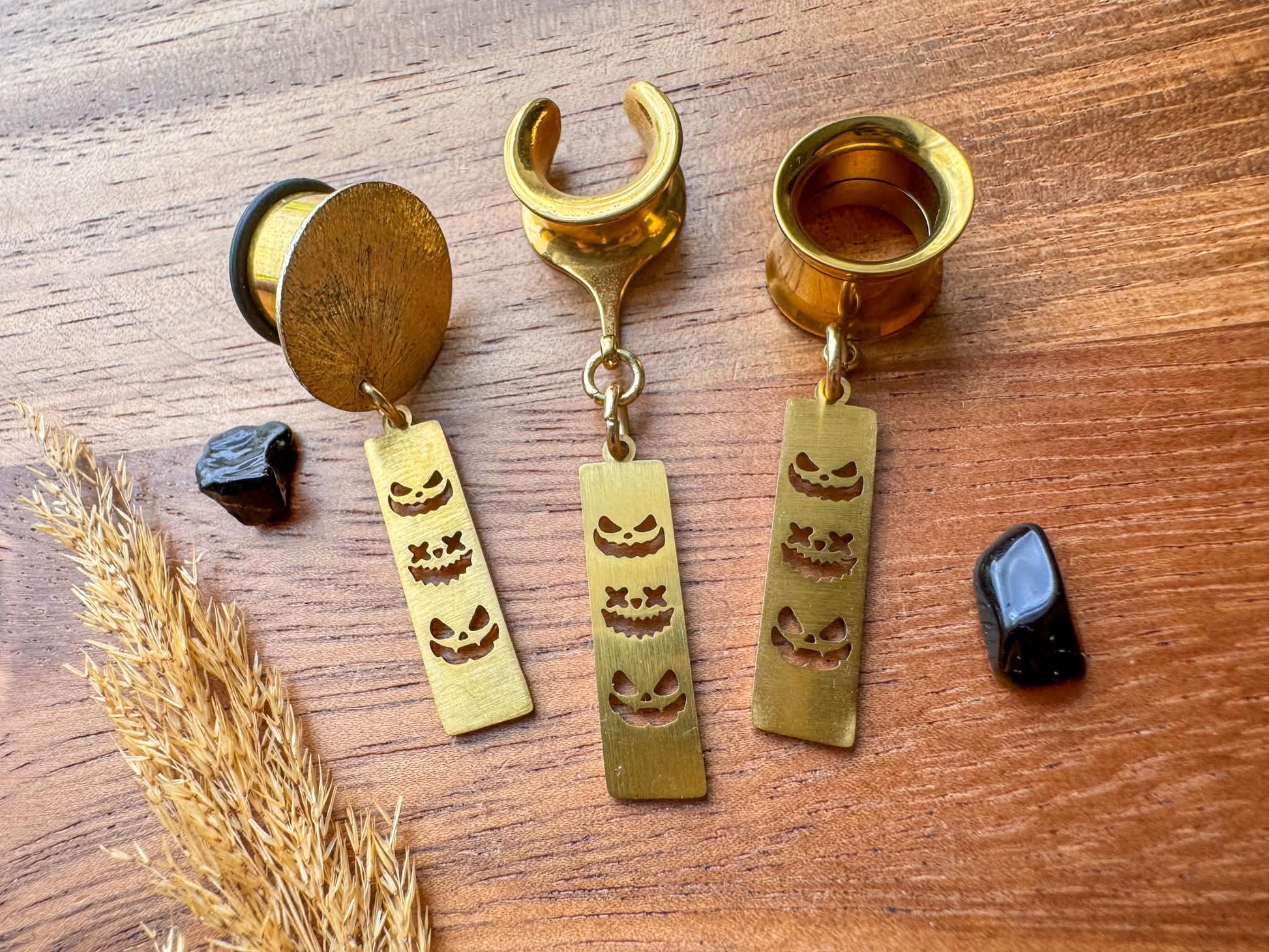 Gold trio jack o' lantern plug earrings with three dangling pumpkin faces for stretched ears.