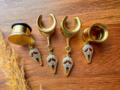 Gold saddle earrings with zircon Halloween masquerade mask charms for stretched ears.