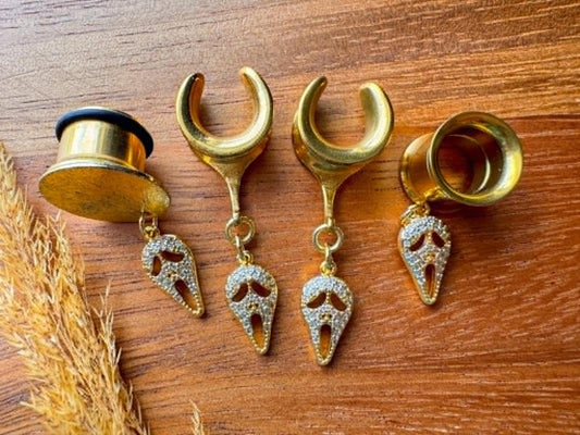 Gold saddle earrings with zircon Halloween masquerade mask charms for stretched ears.