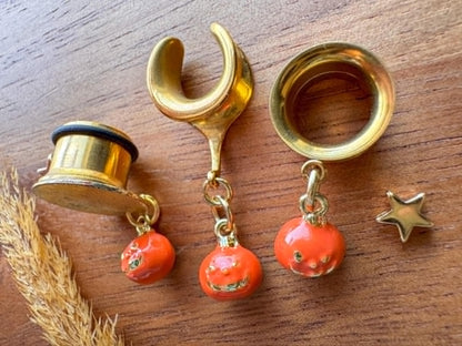 Gold and orange jack o' lantern plug earrings with dangling Halloween pumpkin charms for stretched ears.