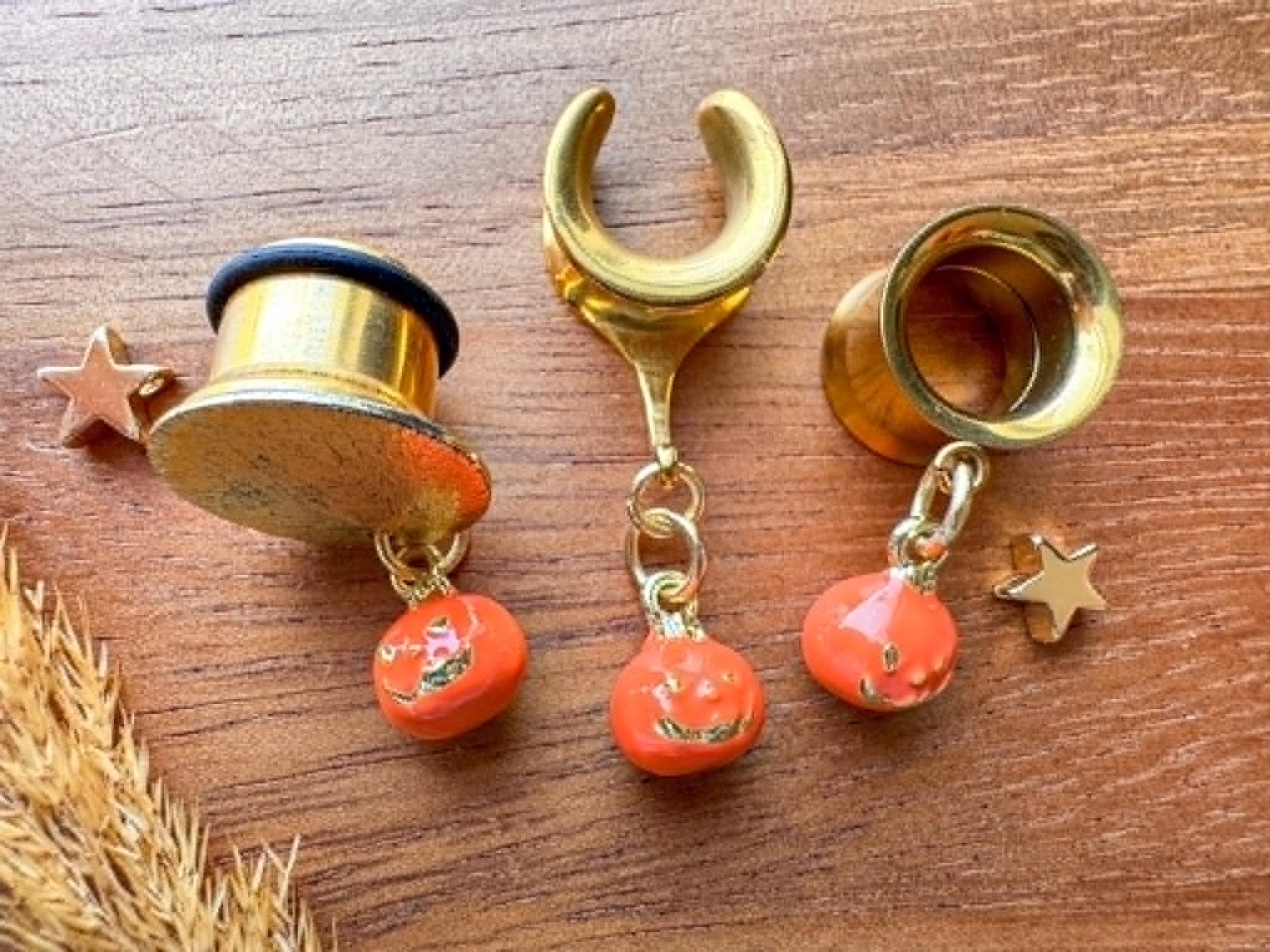 Gold and orange jack o' lantern plug earrings with dangling Halloween pumpkin charms for stretched ears.