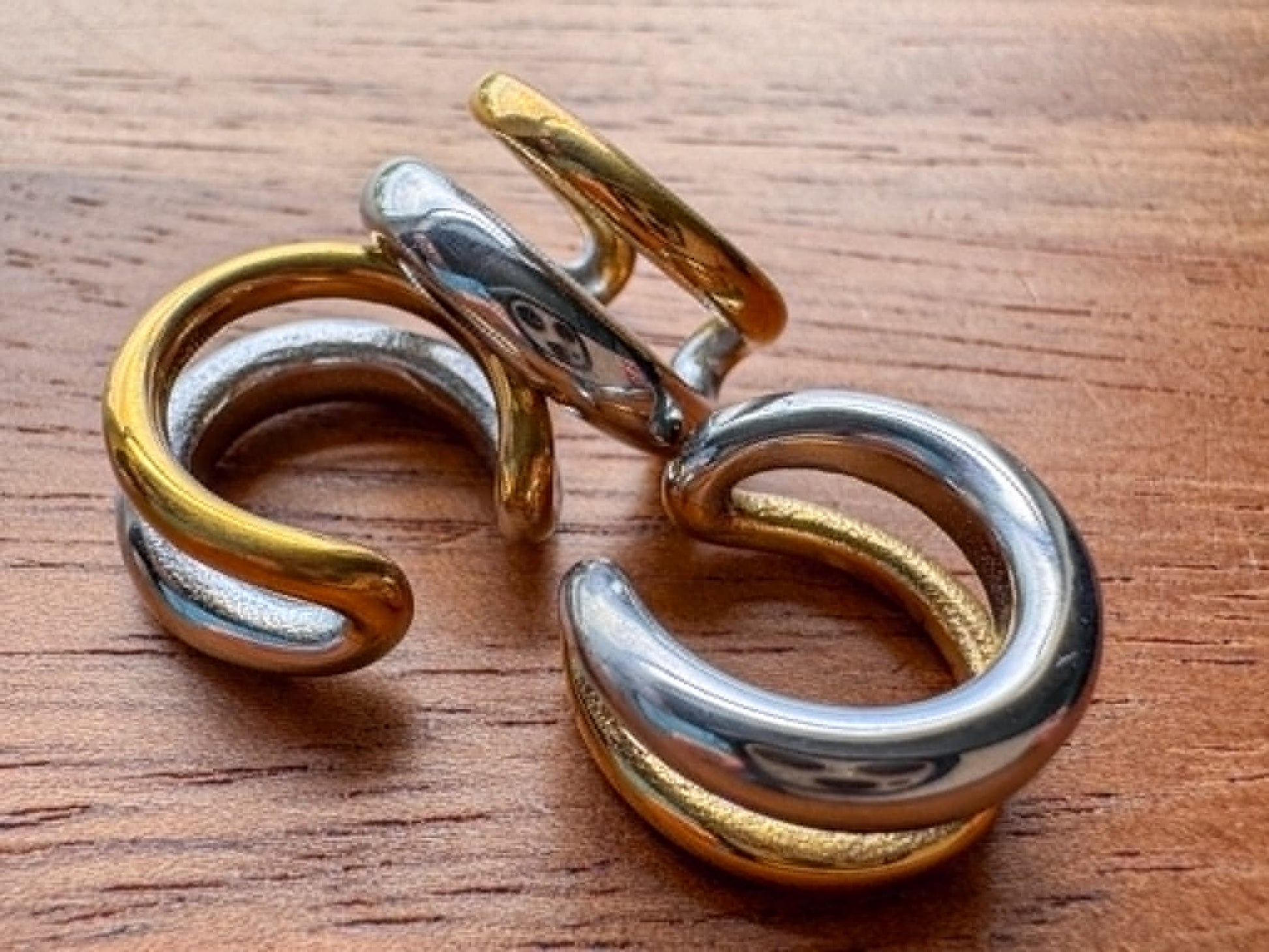Mixed metal double ring ear cuff with silver and gold tones in a stacked no-piercing design.