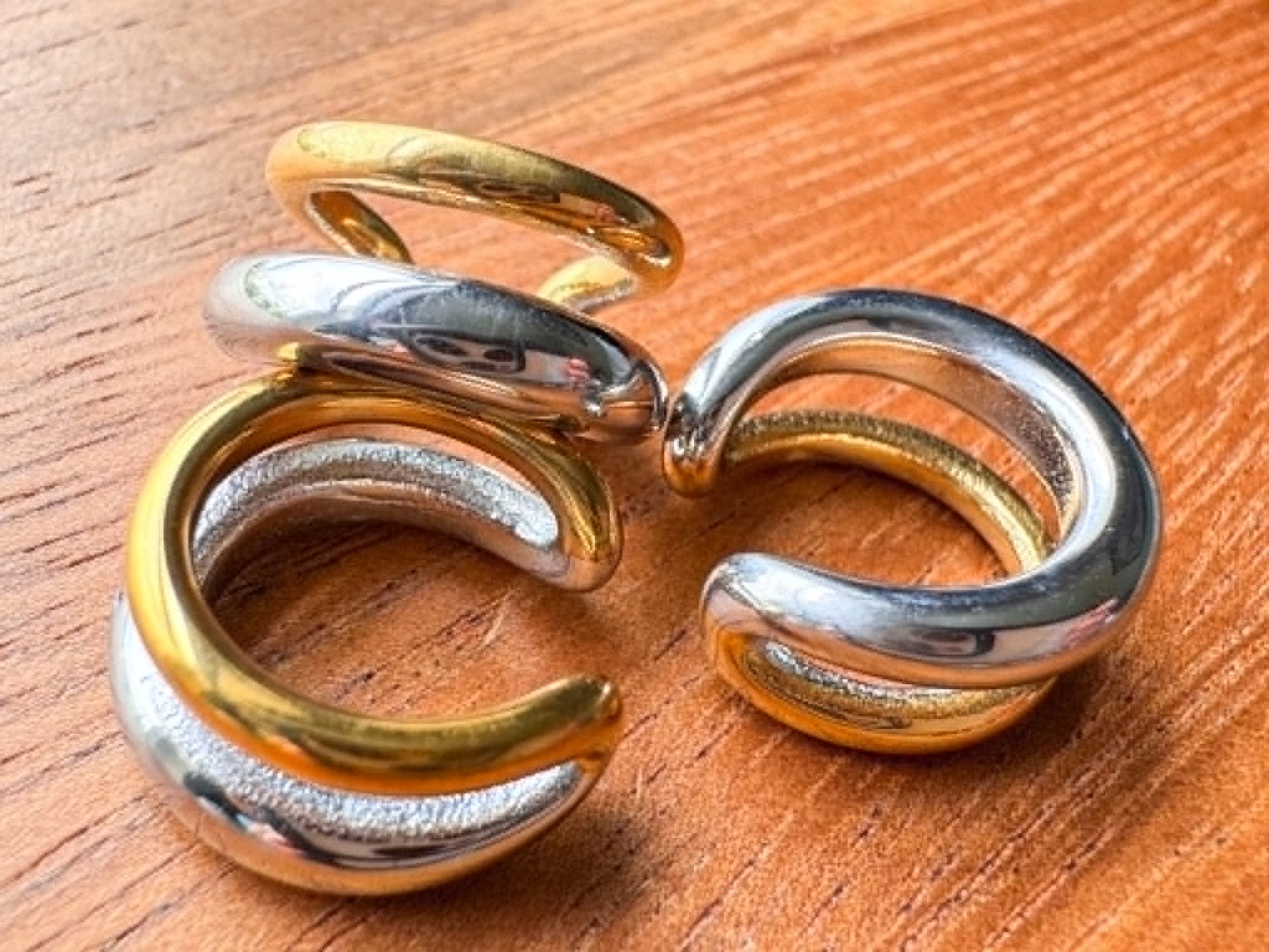 Mixed metal double ring ear cuff with silver and gold tones in a stacked no-piercing design.