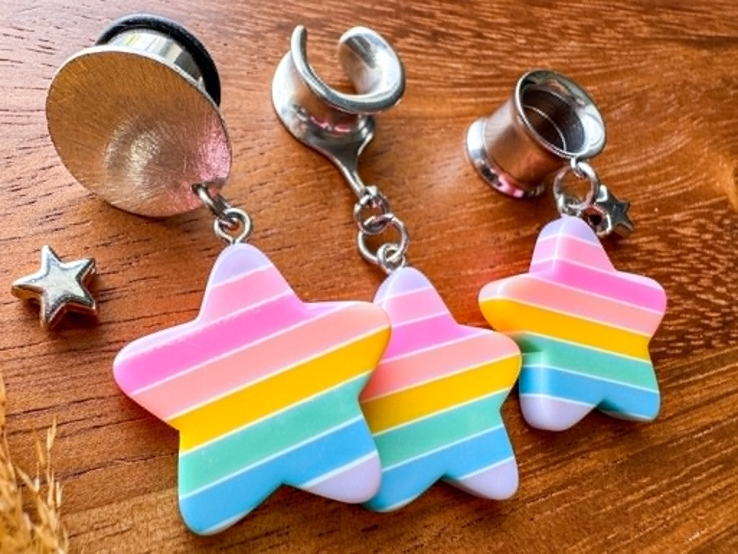Pastel rainbow star plug earrings with colorful celestial charms for stretched ears.