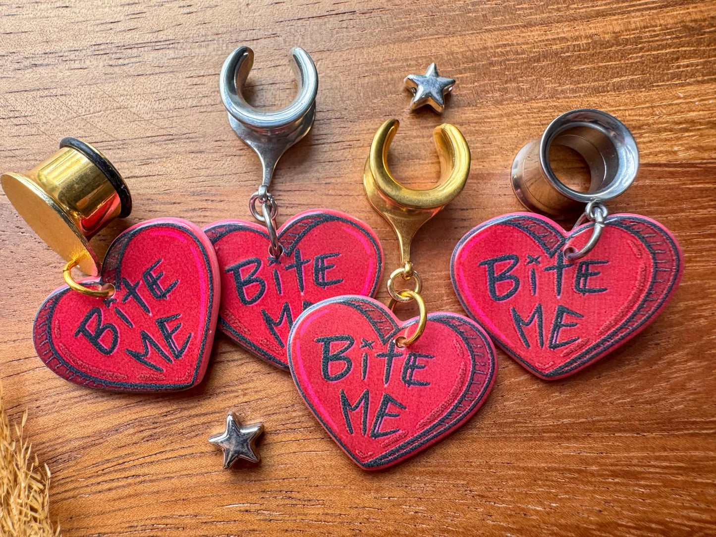 Red Bite Me heart plug earrings with bold heart-shaped dangling charms for stretched ears.