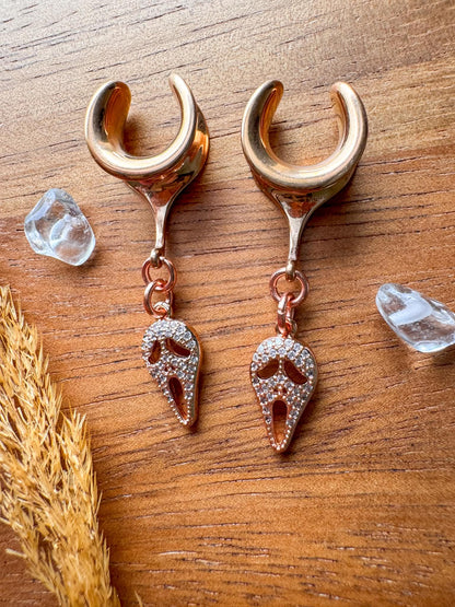Rose gold Halloween mask plug earrings with sparkling masquerade style charms for stretched ears.