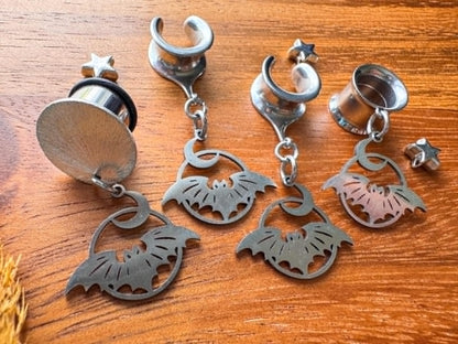 Silver stainless steel bat and crescent moon plug earrings with dangling celestial charms for stretched ears.