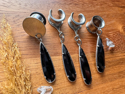 Black glass teardrop plug earrings with silver trim and dangling teardrop charms for stretched ears.