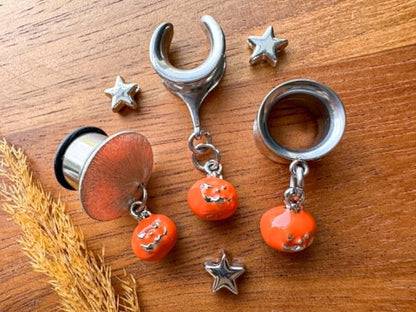 Silver and orange jack o' lantern plug earrings with dangling Halloween pumpkin charms for stretched ears.