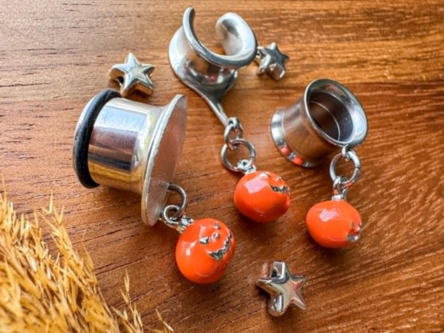Silver and orange jack o' lantern plug earrings with dangling Halloween pumpkin charms for stretched ears.