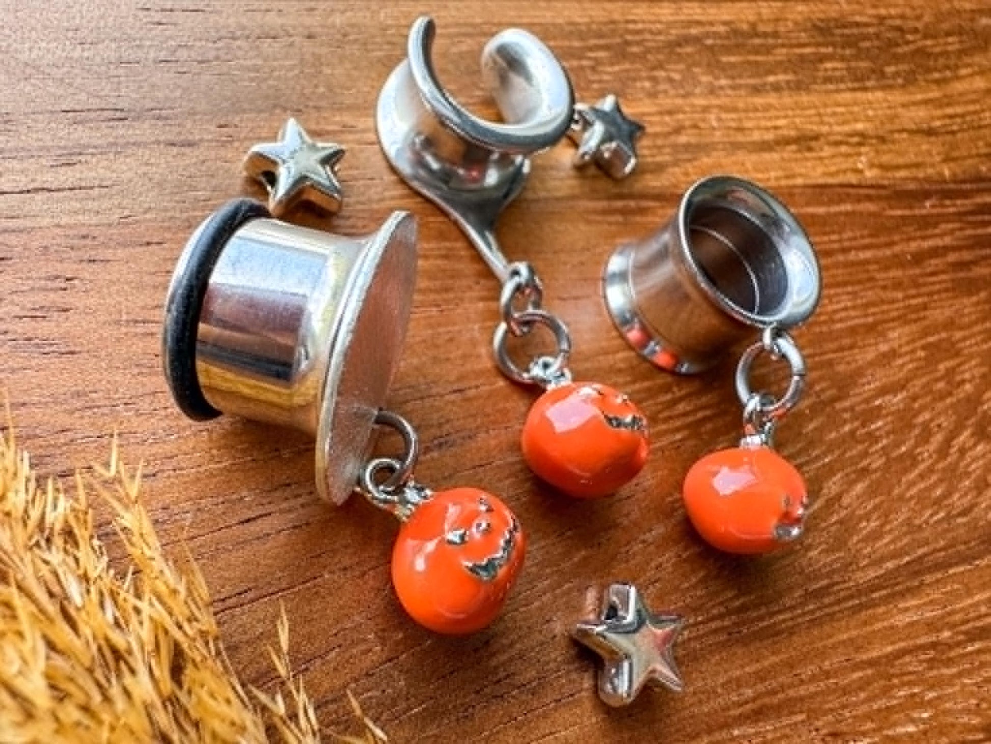 Silver and orange jack o' lantern plug earrings with dangling Halloween pumpkin charms for stretched ears.