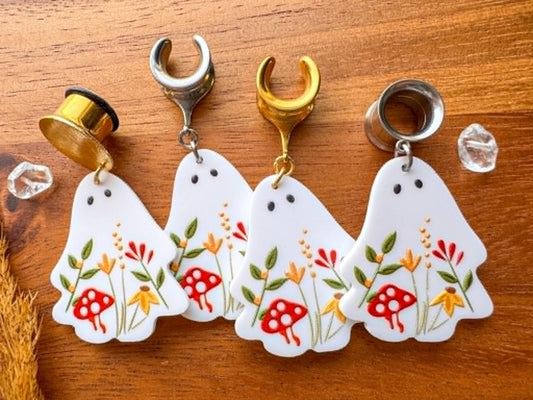 White garden ghost plug earrings with whimsical floral details and dangling ghost charms for stretched ears.